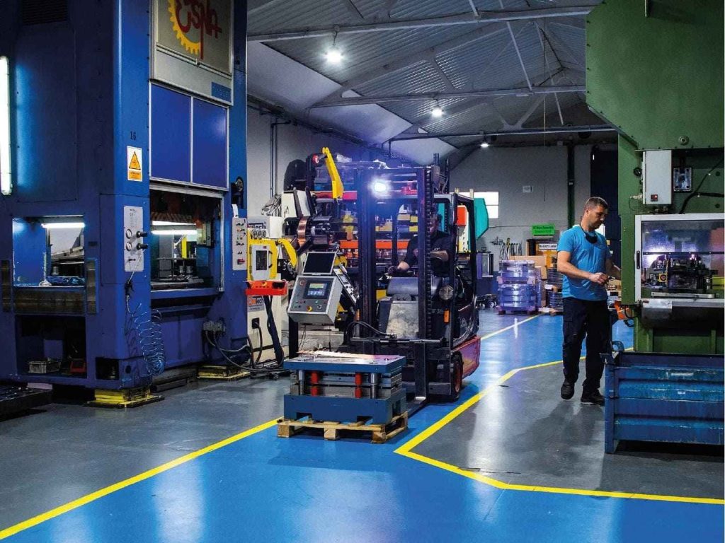 Operario trabajando en proceso de estampación de piezas metálicas en prensa industrial